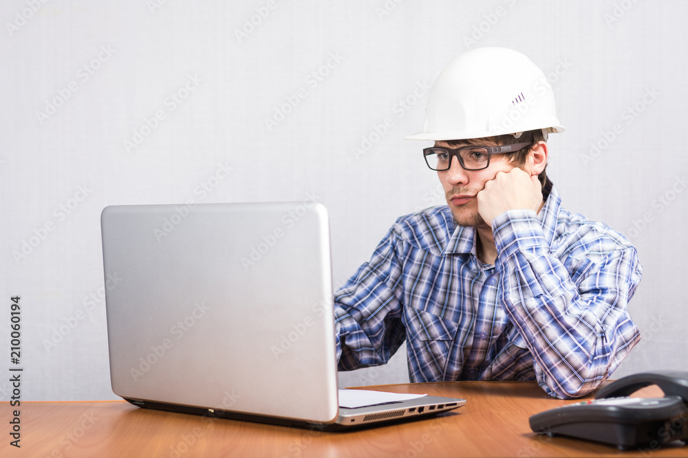the guy in the white helmet works at the computer the guy in the white helmet works at the computer