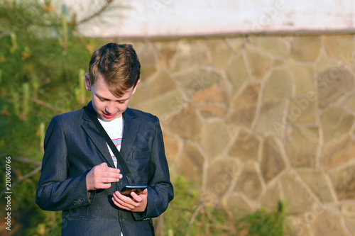 A boy with a smartphone reads a message in a smartphone photo