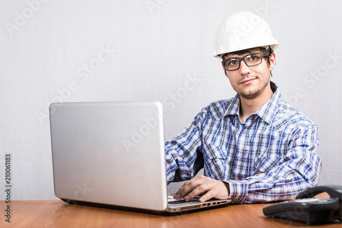 a young guy in a white helmet sitting at the computer
