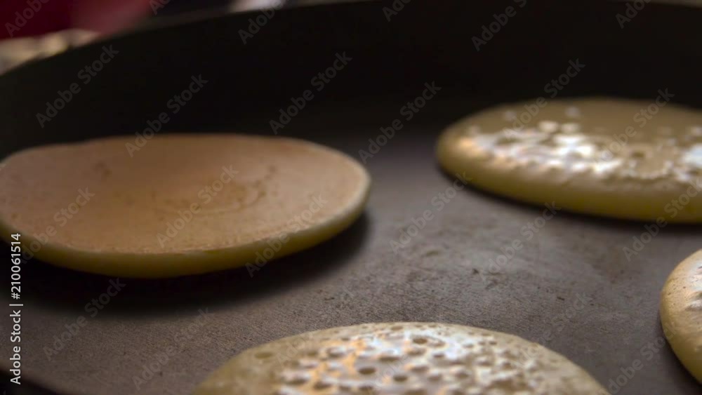 Cooking pancakes on special pan in the kitchen at home. Slow motion. Closeup. Cooking pancakes on special pan in the kitchen at home. Slow motion. Closeup.