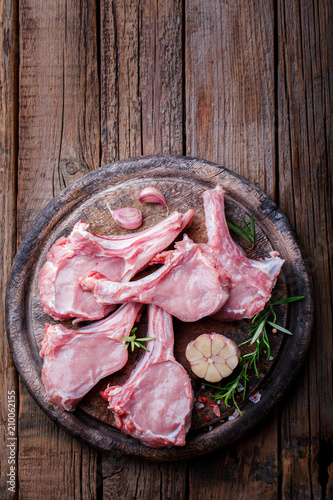 Raw fresh meat Veal rib Steak on bone and meat fork on a wooden vintage background with spices garlic and rosemary Top View Copy space for Text