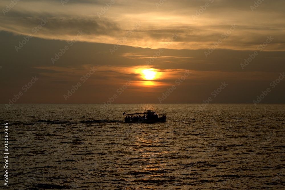 Beautiful orange sunset over the horizon with a fisherman's boat in the scenery 