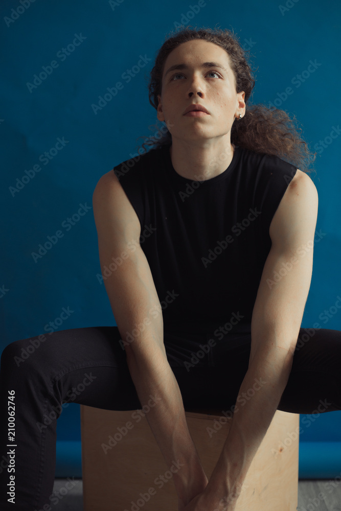 Portraits of a guy with an attractive appearance, curly hair and stylish clothes