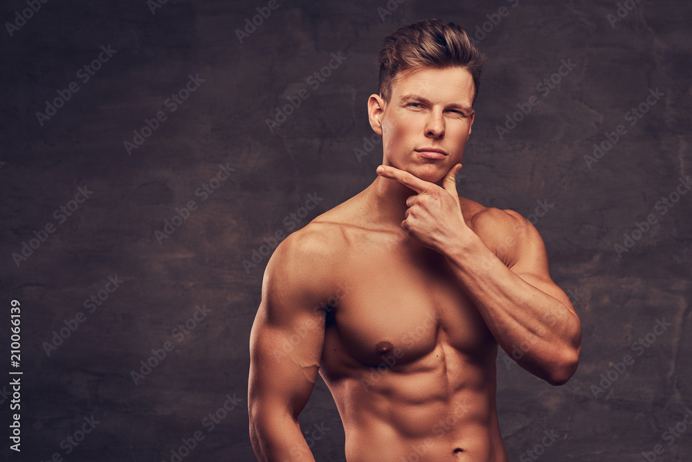 Close-up portrait of a sexy shirtless young man model with a muscular body and stylish haircut posing at a studio. Isolated on dark background. Close-up portrait of a sexy shirtless young man model with a muscular body and stylish haircut posing at a studio. Isolated on dark background.