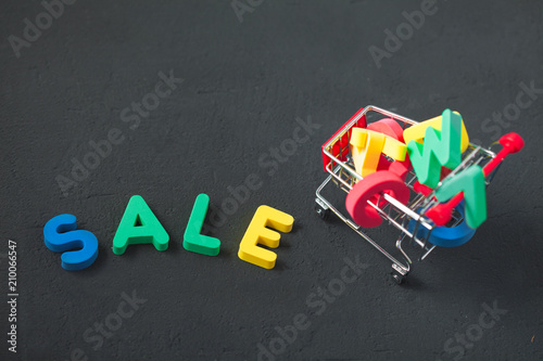 sale, discount, black Friday concept with bright inscription Sale on a dark background, consumer trolley with letters Copyspace Top view photo