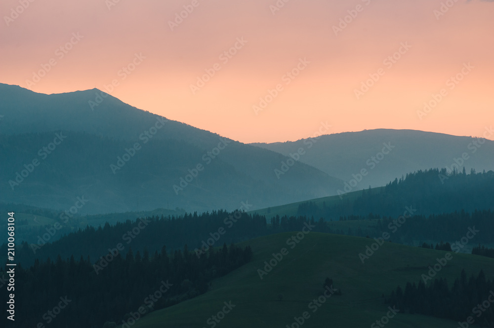 Beautiful dramatic sunrise in the mountains. Landscape with sunlight shining through orange clouds