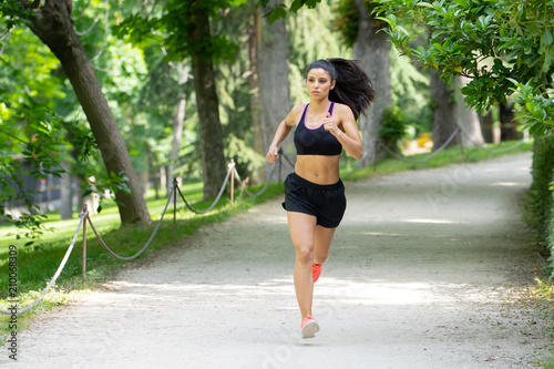 young pretty runner working out in a green city park in exercise fitness concept