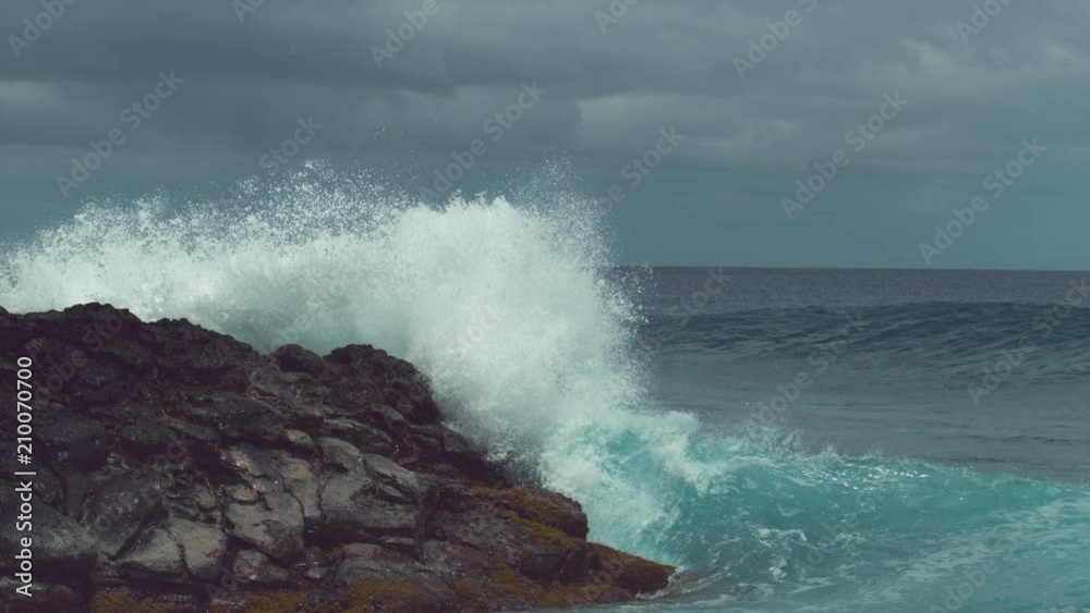 SLOW MOTION: Emerald breaking wave hits the rocky coast with incredible force and splashes high into the air, sending droplets of crystal clear seawater everywhere. Powerful waves near Easter Island. SLOW MOTION: Emerald breaking wave hits the rocky coast with incredible force and splashes high into the air, sending droplets of crystal clear seawater everywhere. Powerful waves near Easter Island.