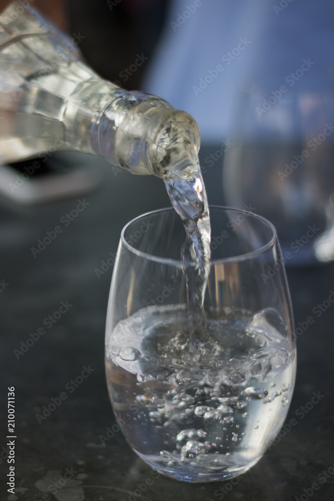 Close-up: clean drinking water is poured from bottle to glass. Vertical image. Close-up: clean drinking water is poured from bottle to glass. Vertical image.