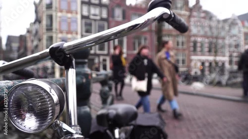 Bicycle is in Amsterdam close up. In the background people walk around the city