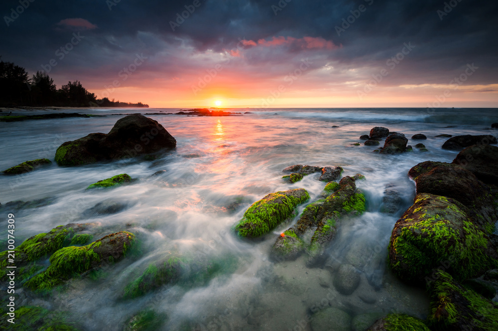 Sunset seascape with rocks covered by green moss. beautiful color with  dramatic sky.