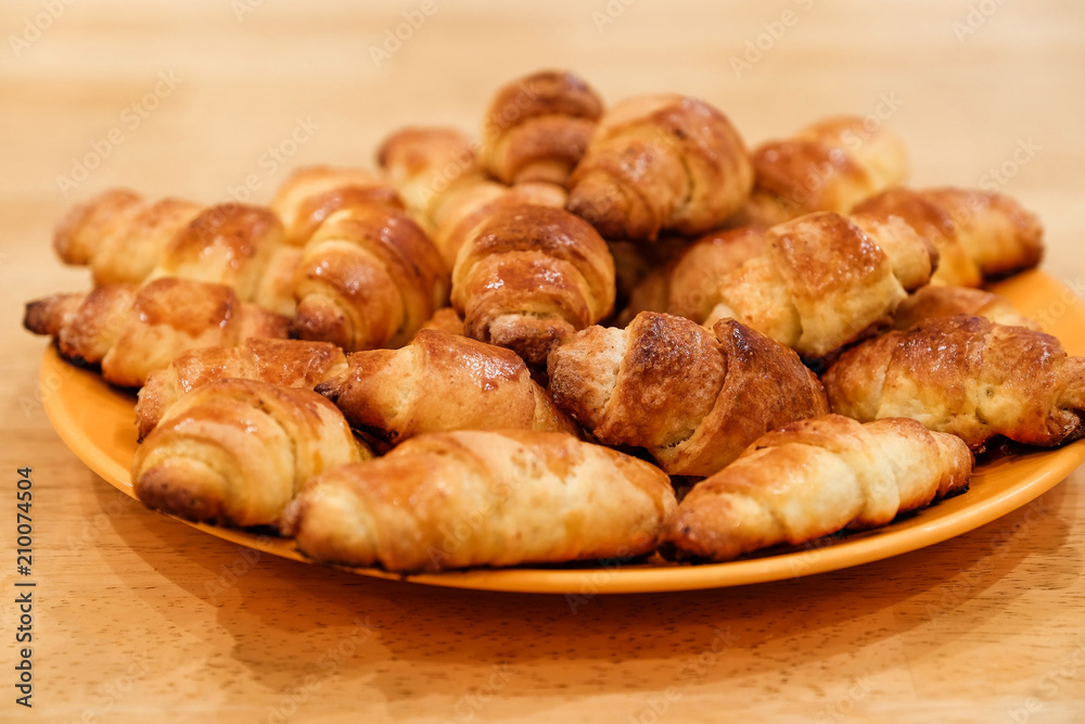 Selective focus on the front small croissant. Small croissants, homemade cakes. Blurred background.