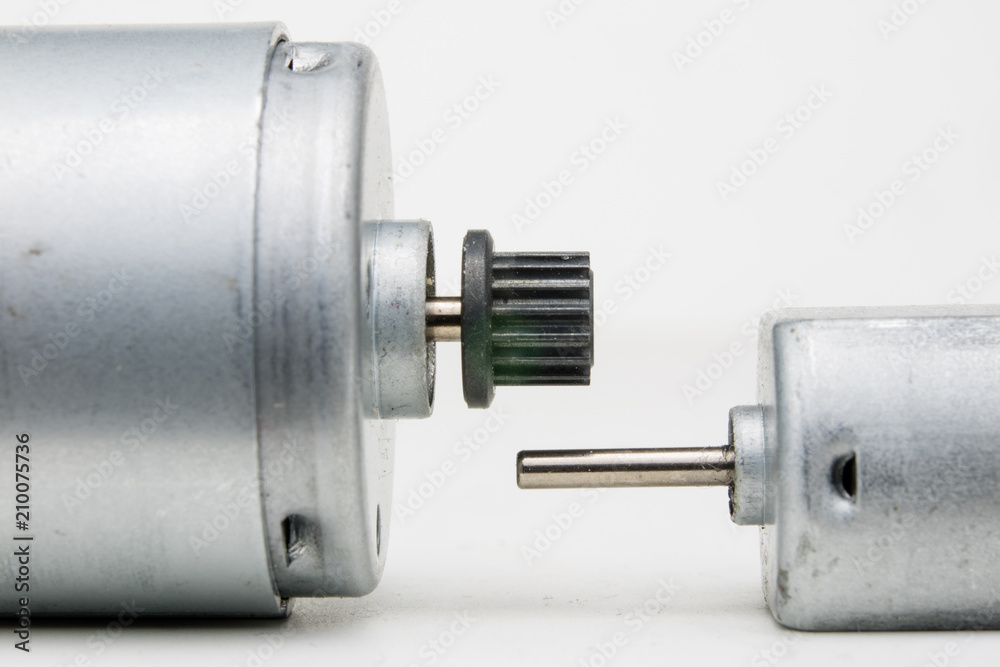 Small electric motor on a white workshop table. Electric drive used in small electrical devices. Small electric motor on a white workshop table. Electric drive used in small electrical devices.