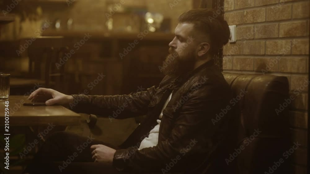 Happy young man speaking by smartphone sitting at the cafe. Young businessman talking on the phone in cafe Happy young man speaking by smartphone sitting at the cafe. Young businessman talking on the phone in cafe