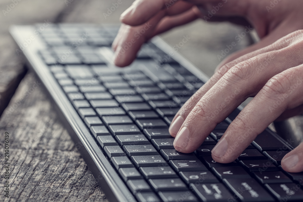 Side view of a man typing on a wireless computer keyboard Side view of a man typing on a wireless computer keyboard