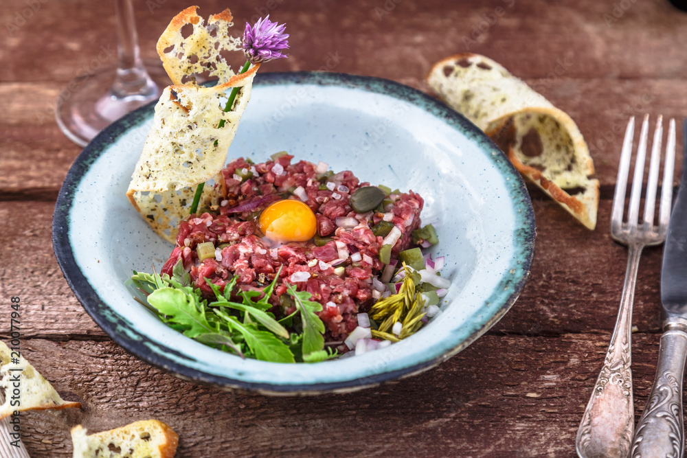 Steak tartare served with raw quail egg yolk and other tartare ingredient. Meat dish. Steak tartare served with raw quail egg yolk and other tartare ingredient. Meat dish.