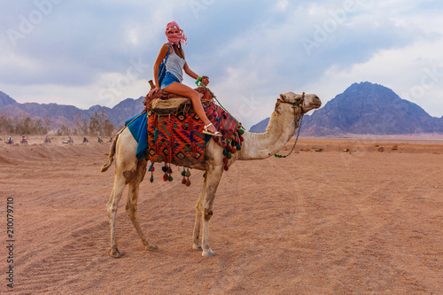Tourist woman in traditional arabian clothes with camel in the Sinai Desert, Sharm el Sheikh, Sinai Peninsula, Egypt.