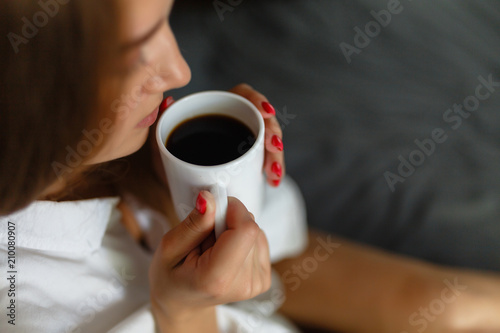 Wallpaper Mural Close-up of the lips of a girl drinking coffee while sitting on the bed. Sunny lazy morning in bed. White mug with hot coffee in the hands of a young girl. Breakfast in bed. Torontodigital.ca