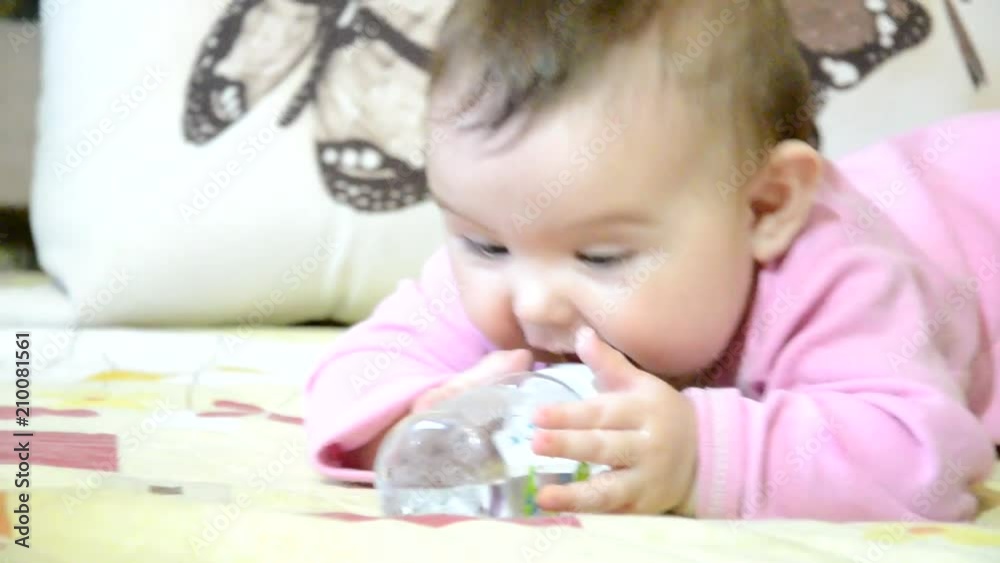 Cute baby girl showing tongue, the baby crawls on the couch, sucks a pacifier, a bottle, baby food, gets up from the hand, a child up to a year, todler Cute baby girl showing tongue, the baby crawls on the couch, sucks a pacifier, a bottle, baby food, gets up from the hand, a child up to a year, todler