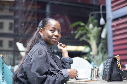 Black girl having a cup of tea on a modern terrace © jos_persona