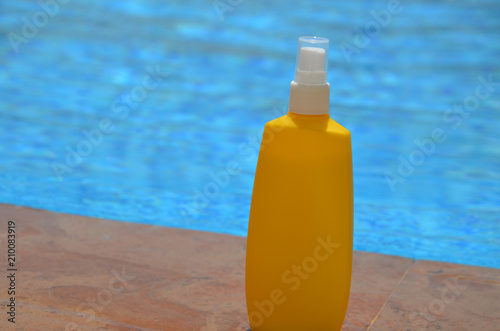 summer-Yellow sunblock cream in blue outdoor swimming pool photo