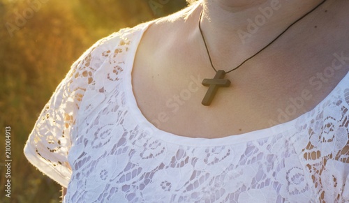 Chain with a cross on a neck . Christian cross on sunset background .  Religion background . Paradise heaven . Light in sky . Happy Easter . 