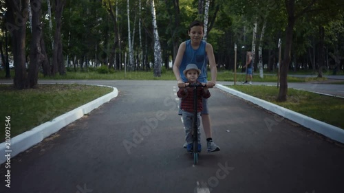 Wallpaper Mural two brothers riding a kick scooter in a summer park. Torontodigital.ca