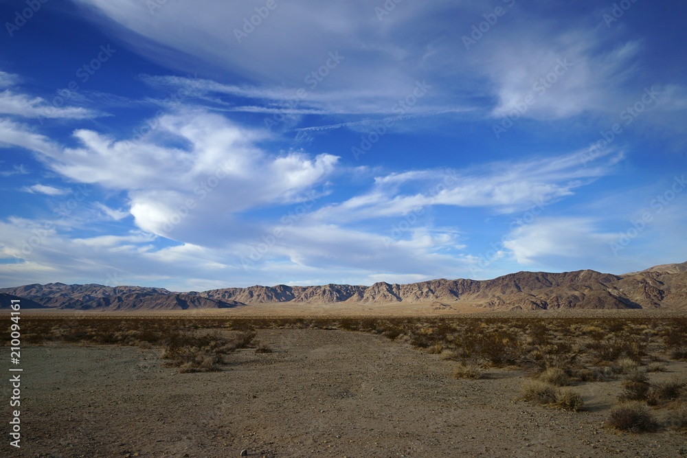Evening view from Pinto Basin Rd, Joshua Tree National Park with dramatic cloud formations and mountains in the distance