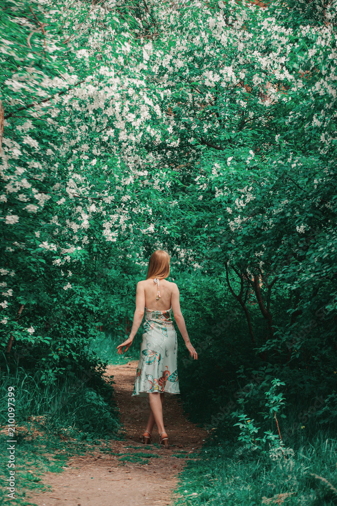 Fototapeta premium young woman in forest on a background of green foliage. Fashion for women