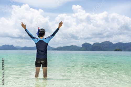 Backside of Handsome man extend arms and standing on the beach In the midst of the blue sky Handsome Asian man enjoying a holiday on the sea shore concept of Summer