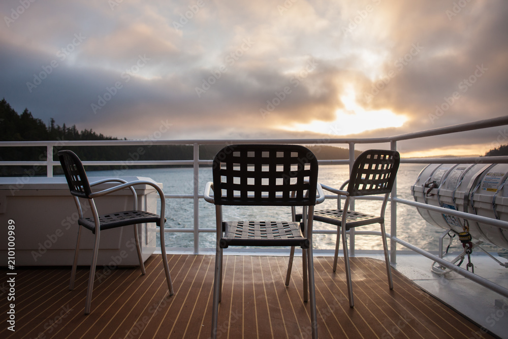Outdoor chairs on the deck of a cruise ship with sunset behind