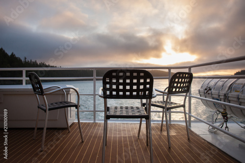 Outdoor chairs on the deck of a cruise ship with sunset behind © DaiMar