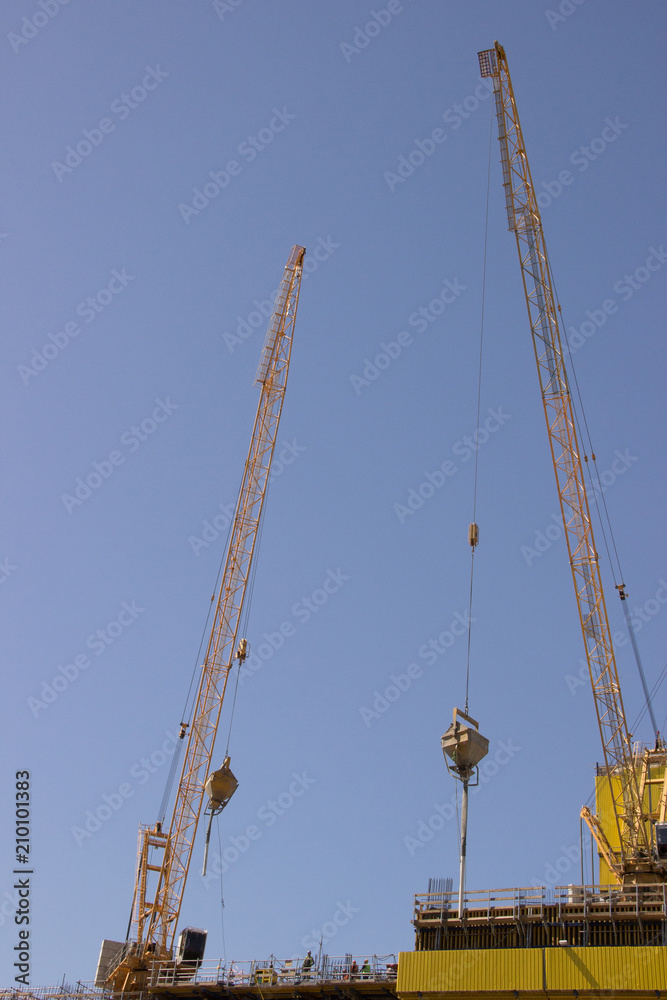 Construction of a modern high-rise building with cranes against the sky in summer Construction of a modern high-rise building with cranes against the sky in summer