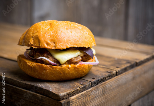 Tasty burger with basil on the rustic wooden background. Selective focus. Shallow depth of field.