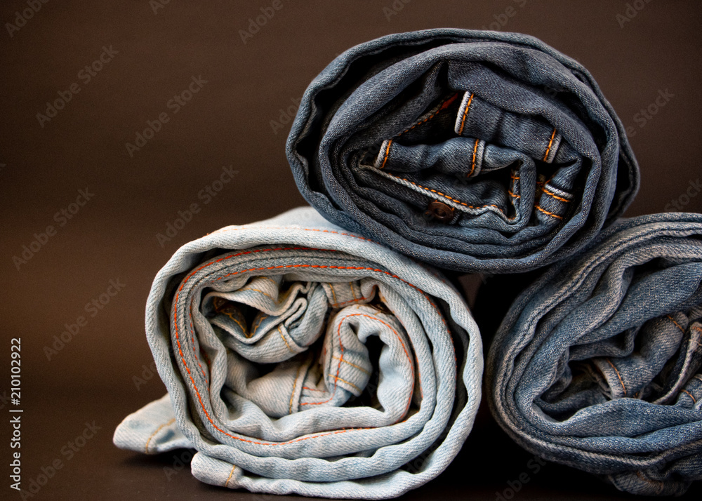 Stack of blue denim jeans on a dark background. Closeup photo of apparel.