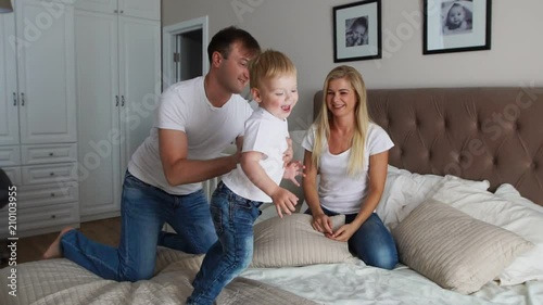 Parents having fun with their little daughter on bed. Family spending time at the morning photo