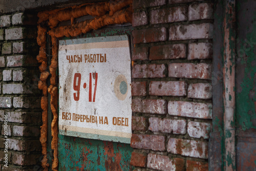 Plate in Russian on the brick wall: opening hours 9-17
