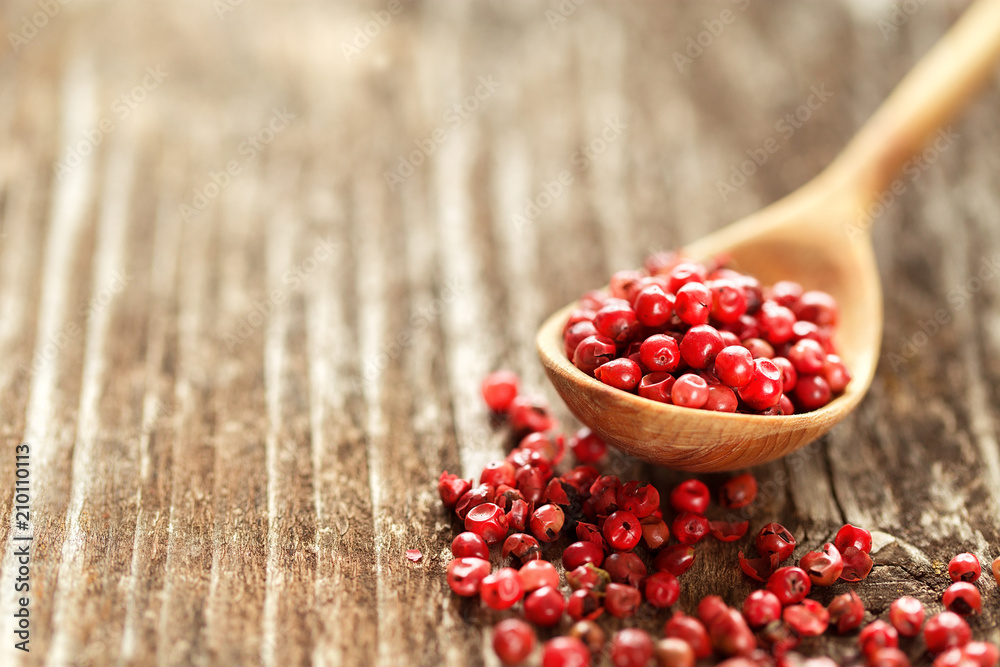 Red peppercorns in a spoon on wooden table. Red peppercorns in a spoon on wooden table.