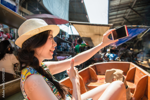Woman taking selfie with floating market.