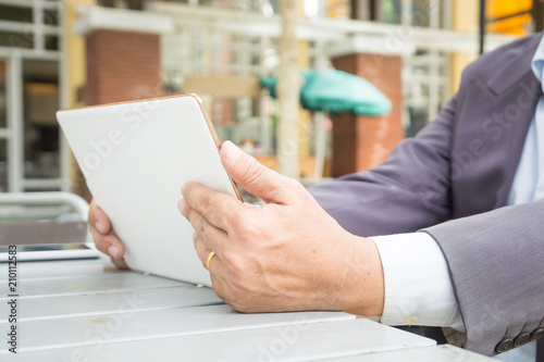 Asian Businessman in Suit use Digital Wireless Tablet outdoor in Public