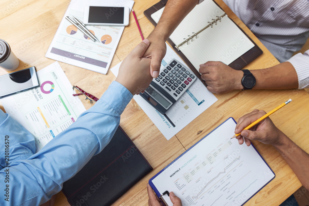 Business and finance concept of office working,Top view of Teamwork of Businessmen shaking hand and discussing business investment plan in office Business and finance concept of office working,Top view of Teamwork of Businessmen shaking hand and discussing business investment plan in office