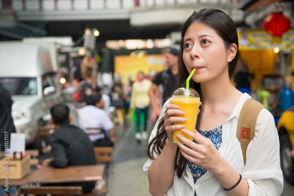 Fototapeta premium woman drinking the mango juice in the street