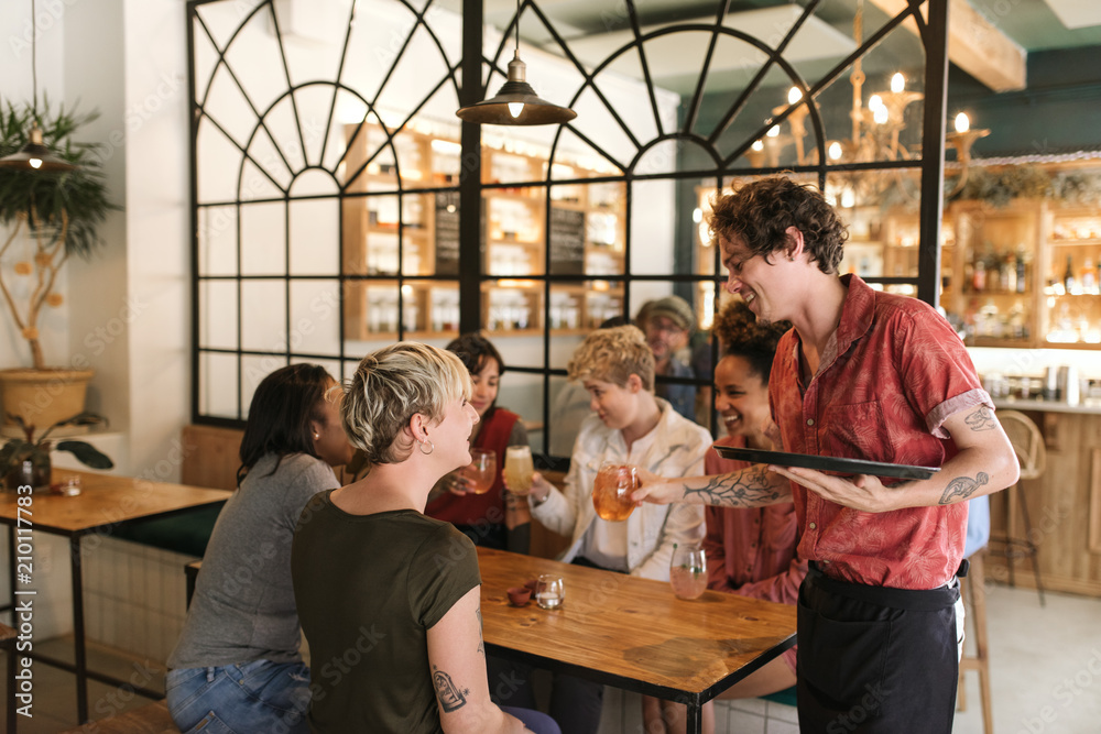 Diverse group of girlfriends ordering drinks from a bistro waiter Diverse group of girlfriends ordering drinks from a bistro waiter