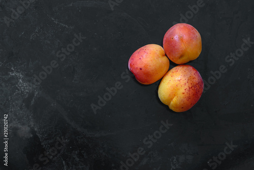 Apricots top view flatlay on dark rustic background; summer