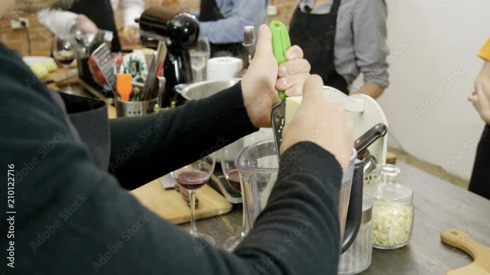 The man rubbing parmesan cheese on the metal grater for pesto sauce at cooking master class. 4K The man rubbing parmesan cheese on the metal grater for pesto sauce at cooking master class. 4K