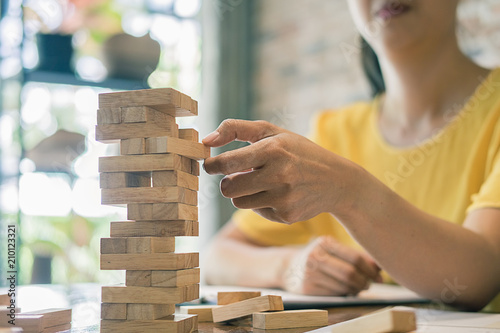 Hand of business man planning, risk and strategy in business.Businessman gambling placing wooden block on a tower.