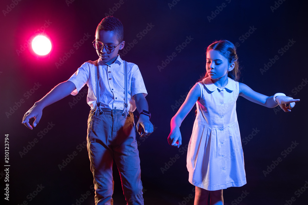 Powers of imagination. Serious lovely boy and a girl standing next to each other and pressing imaginary buttons Powers of imagination. Serious lovely boy and a girl standing next to each other and pressing imaginary buttons