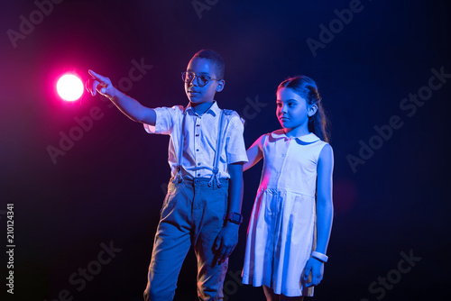 We are happy. Inspired afro-american boy pressing imaginary buttons and a girl standing near him