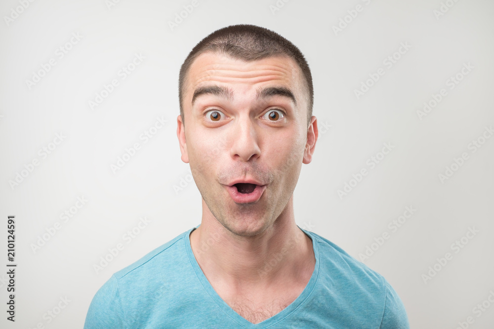 surprised young man in polo t-shirt over gray background. surprised young man in polo t-shirt over gray background.