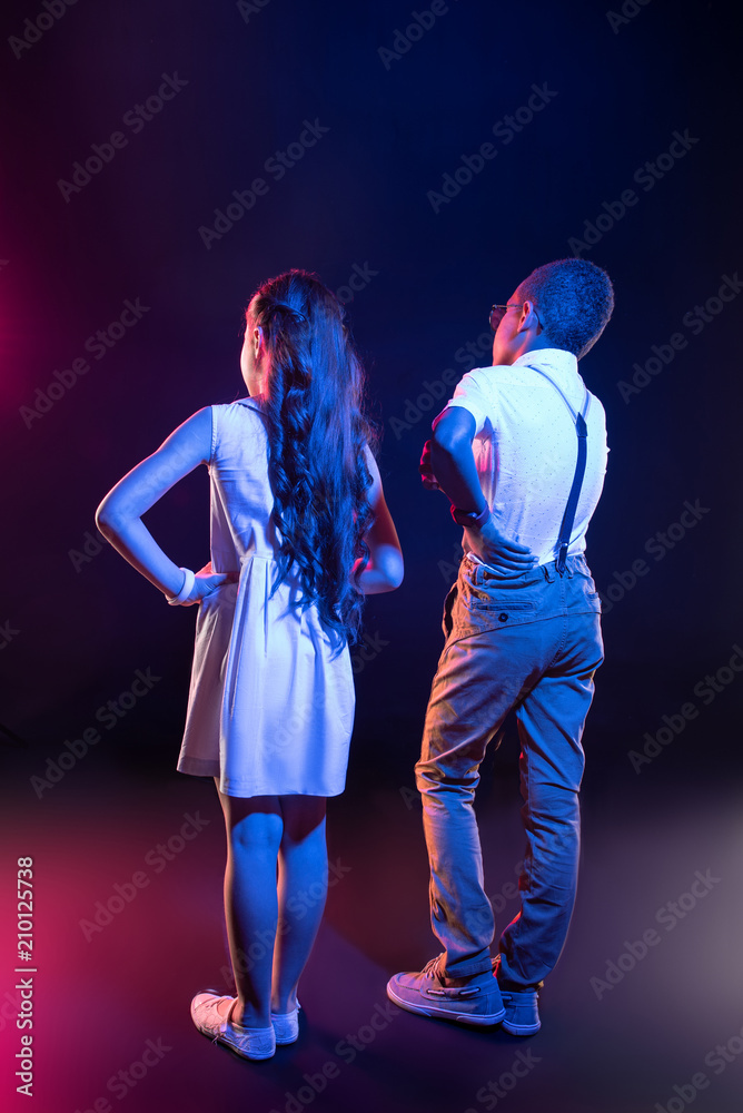 Fototapeta premium We are friends. Smart long-haired girl having her hand on her waist and a boy standing near her